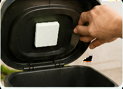 Hand placing a white sponge insert inside a trash can lid